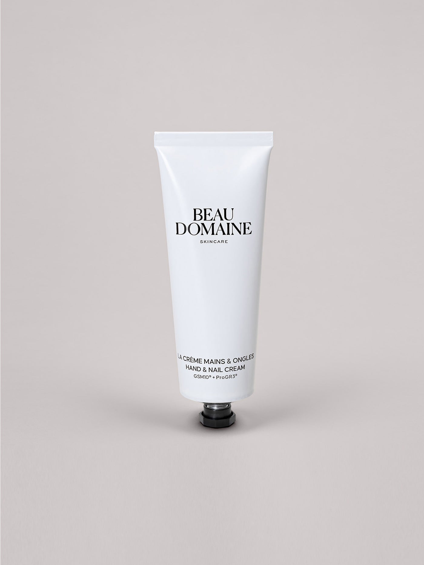 Tube blanc de crème mains et ongles Beau Domaine sur fond gris clair.