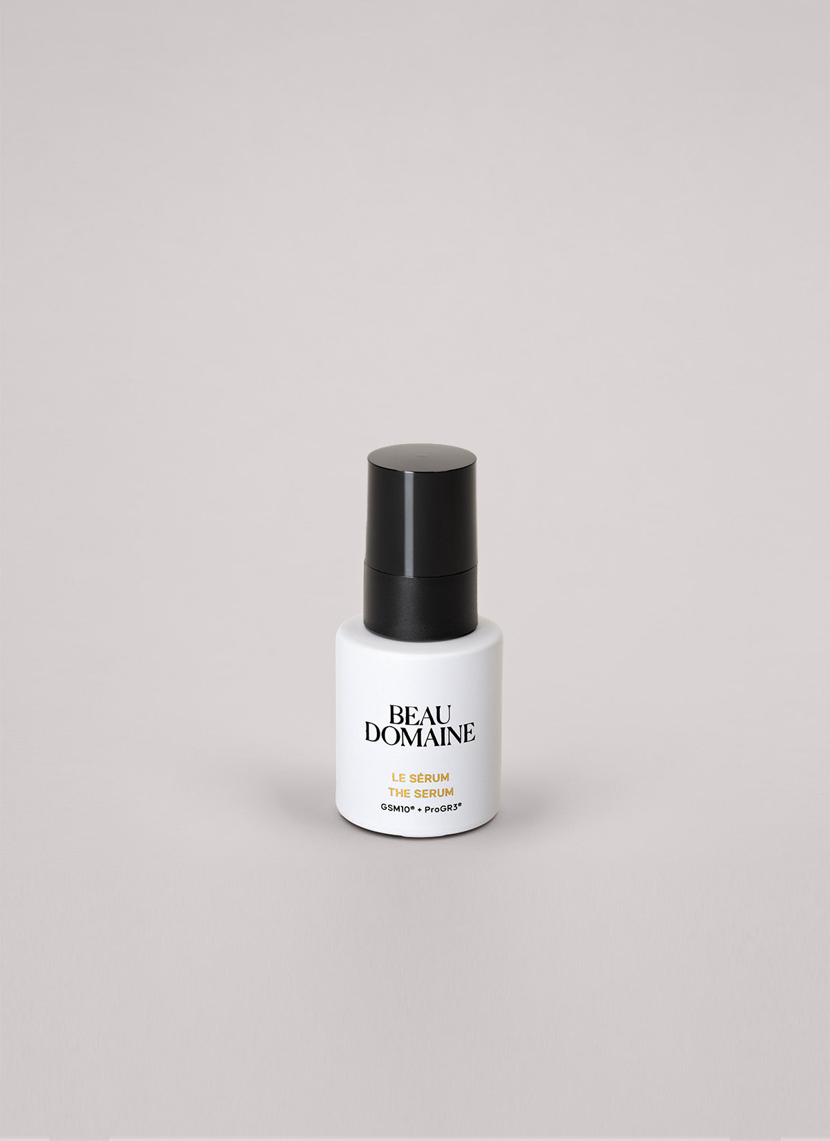 Flacon de sérum blanc avec bouchon noir sur fond gris clair